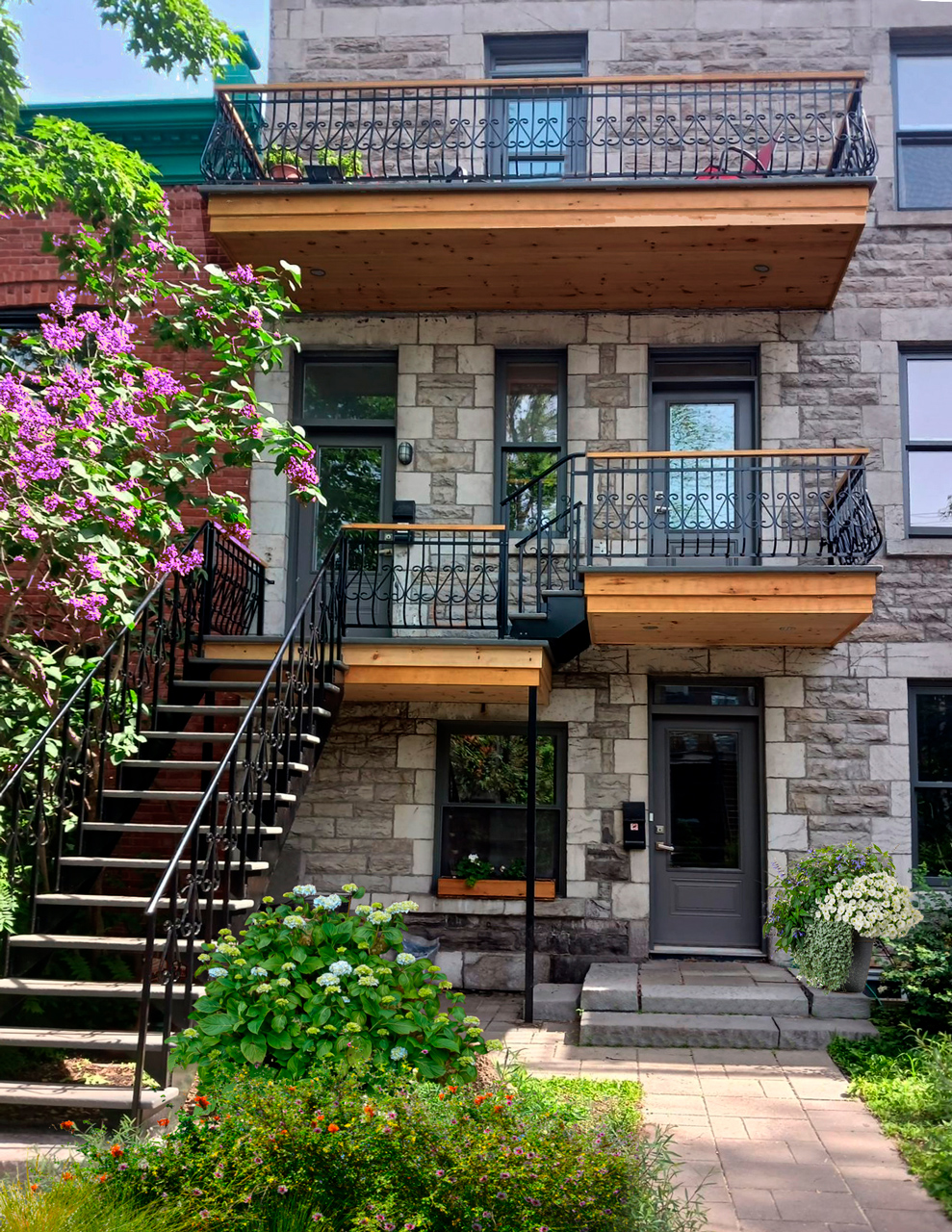 Escalier Mtl - Fabriquant d'escalier extériuer à Montréal - Vue d’une façade de triplex aux escaliers et balcons en bois